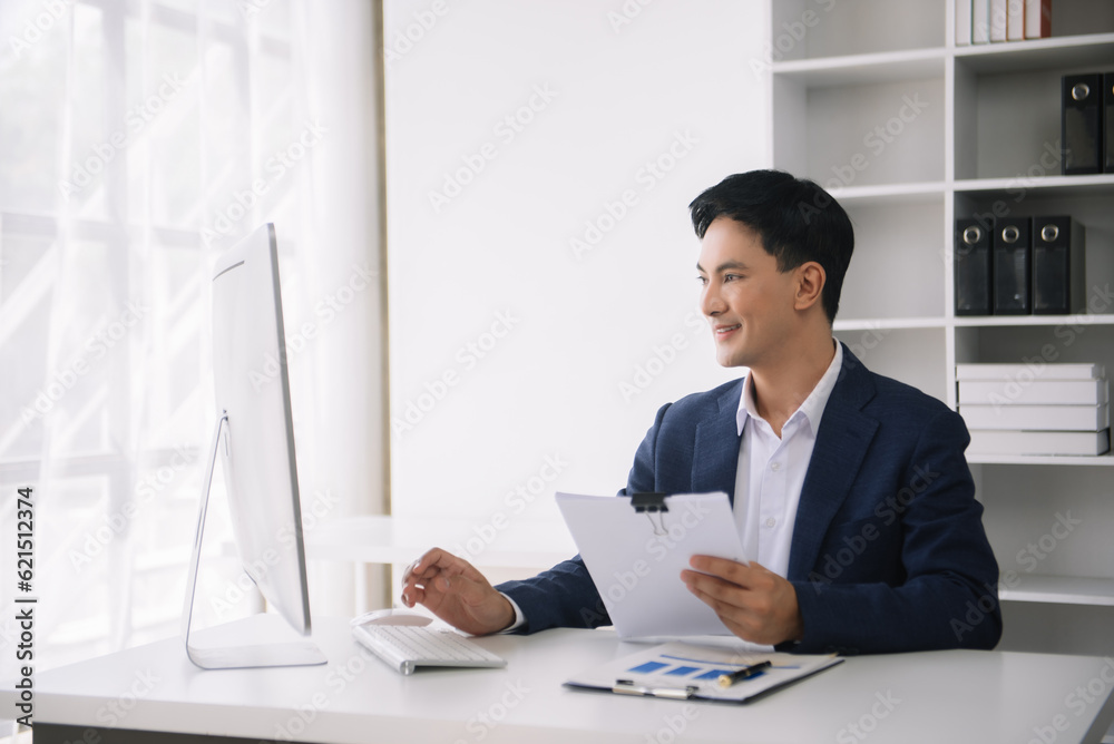 Confident Asian man with a smile standing holding notepad and tablet at the modern office. Confident Asian man with a smile standing holding notepad and tablet at the modern office.