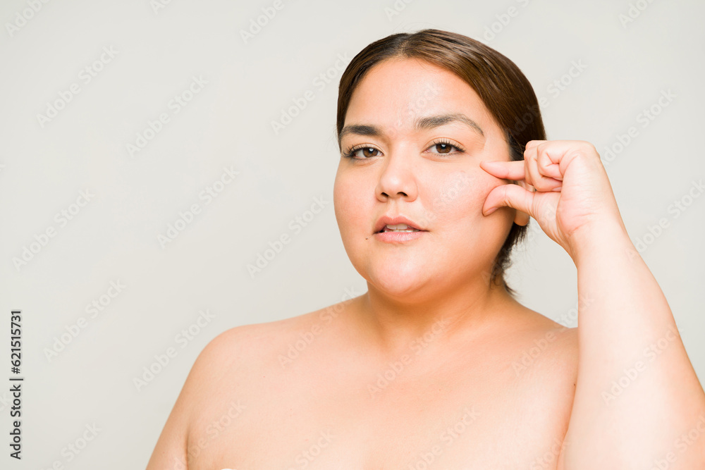 Aging obese woman in her 30s doing her skin care for wrinkles