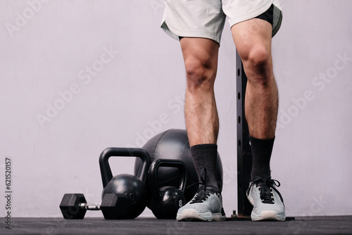 fitness equipment dumbbell kettlebell on black background and young male exerciser