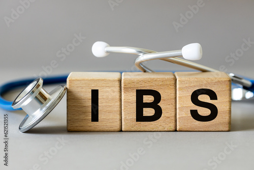 Medical stethoscope and wooden blocks with the inscription IBS, Abbreviation for irritable bowel syndrome, a chronic disease of the gastrointestinal tract of a functional nature, gray background photo