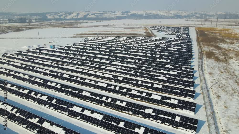 Aerial view of electrical power plant with solar panels covered with snow melting down in winter end for producing clean energy. Concept of low effectivity of renewable electricity in northern region Aerial view of electrical power plant with solar panels covered with snow melting down in winter end for producing clean energy. Concept of low effectivity of renewable electricity in northern region