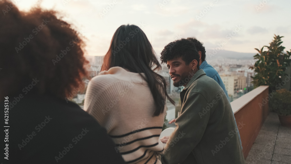 Guys and girls at the party, looking at the beautiful views and talking standing on the terrace, friendly party holiday at sunset