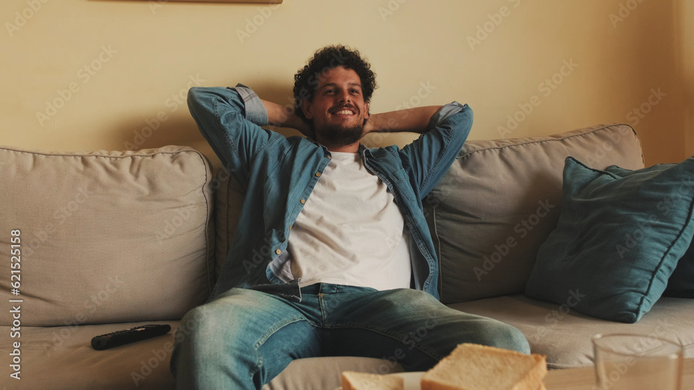 Guy dressed in denim shirt has lunch, sits in the living room and emotionally watches sports game on TV Guy dressed in denim shirt has lunch, sits in the living room and emotionally watches sports game on TV