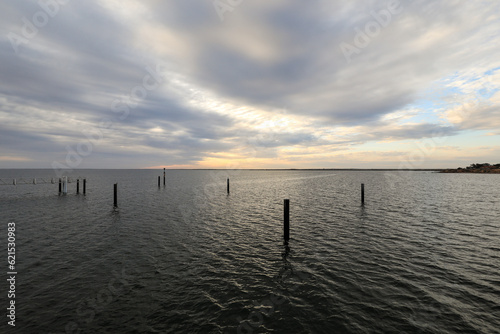 Scenic view of pilons in ocean beneath stormy sky at sunset