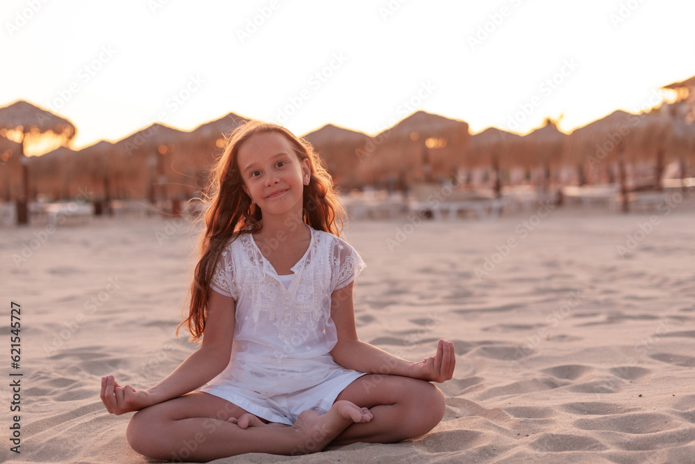 beautiful caucasian girl at sunset on the beach doing yoga, dressed in all white