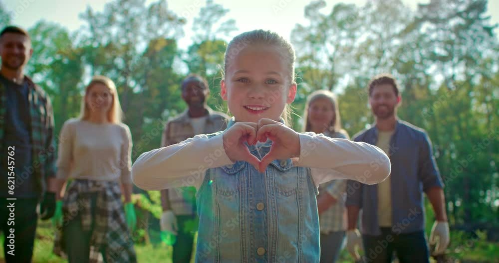 Portrait of little cute girl volunteer standing and showing heart gesture. Joyful child help to save environment. Team of young people for eco friendly help and waste management.