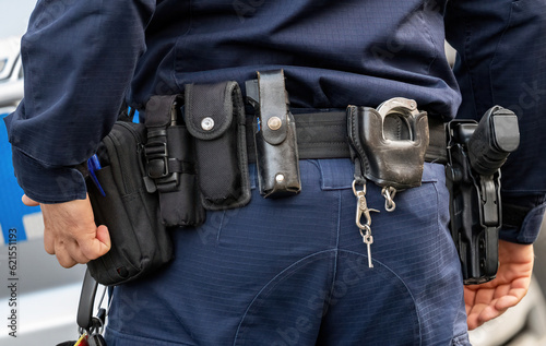 Policeman, police equipment utility belt with a gun, pepper spray and various accessories, detail shot, closeup seen from behind Police officer tools simple concept, emergency services job, occupation photo