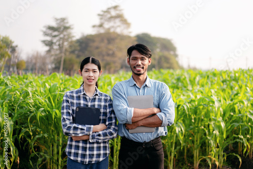 Smart farmers couple holding laptop and digital tablet to examin photo