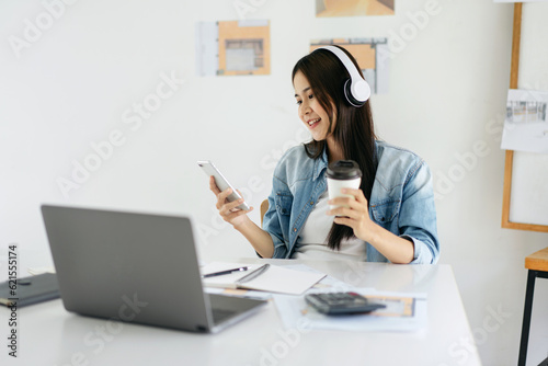 Woman architect drinking coffee and wearing headphone to listeni photo