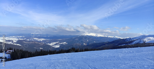 Ski resort in the mountains. Flat snow, fir trees. Blue sky, sunny winter day. Mountain view, horizon over land. Carpathian mountains, Dragobrat, Ukraine. © Olha