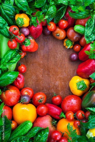 Frame of fresh ripe colorful seasonal vegetables-tomatoes, bell peppers, cucumbers and herbs, top view