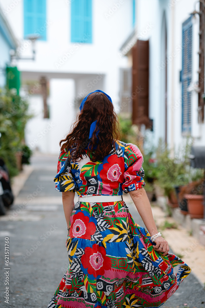 Woman in a Bright Colorful Dress Walking Through a Cozy Greek Street. Woman in a Bright Colorful Dress Walking Through a Cozy Greek Street.
