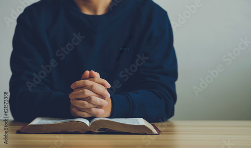 Картината върху платно Man hands praying to god on the open bible on a wooden table