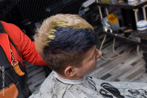 Client young guy in barbershop with stylish fashionable hairstyle crop color creative hair coloring in salon © Andrey