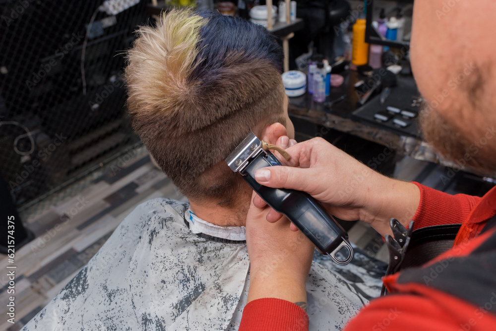 The hands of a man, a master of his craft, a barber, make a fashionable stylish haircut for a young guy, a client of a hairdresser