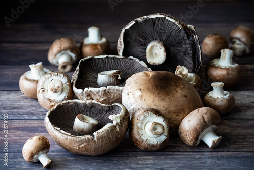 An assortment of portobello and cremini mushrooms against a dark background.
