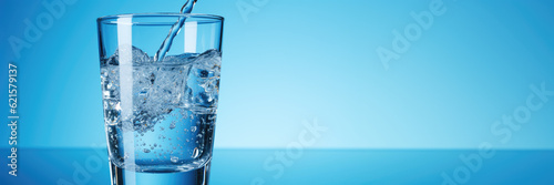 Pouring water from bottle into glass on blue background and copy space