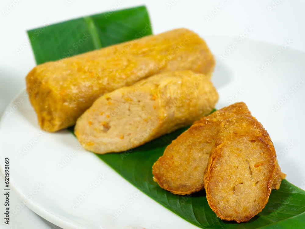 Concept photo of kekian,hekeng or ngohiong food made from minced meat wrapped in steamed bean curd skin served with sauce on the kitchen table.Some materials,bamboo steamer, white wall as background. 