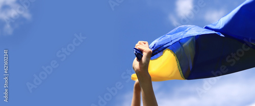 Fotografia Women's hands with the Ukrainian flag against the sky