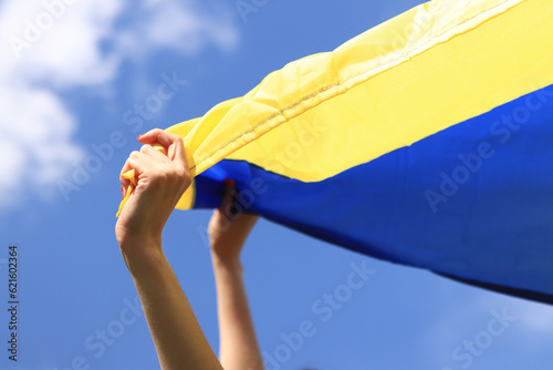 Yellow and blue flag of Ukraine in the woman's hands. Fluttering blue and yellow flag of Ukraine against sky background. Celebrate Constitution Independence flag day photo