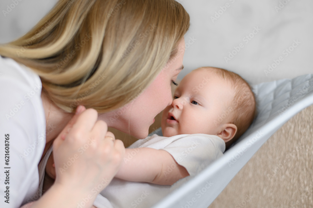 A happy child lies in a children's deck chair,smiles and is happy to see mom,mom talks to the baby. Childhood,motherhood A happy child lies in a children's deck chair,smiles and is happy to see mom,mom talks to the baby. Childhood,motherhood