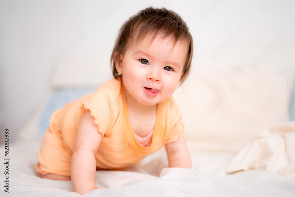 lifestyle home portrait of happy and adorable 9 months old baby girl looking at the camera in funny face expression on white background crawling on bed lifestyle home portrait of happy and adorable 9 months old baby girl looking at the camera in funny face expression on white background crawling on bed