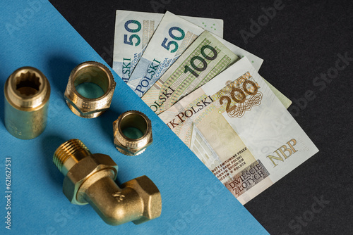 warsaw, poland - 07 07 2023: Polish banknotes of PLN on a black and blue background, next to the brass hydraulic connectors (selective focus)