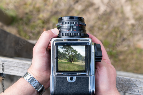 A man takes a photo nature with a vintage viewfinder camera.