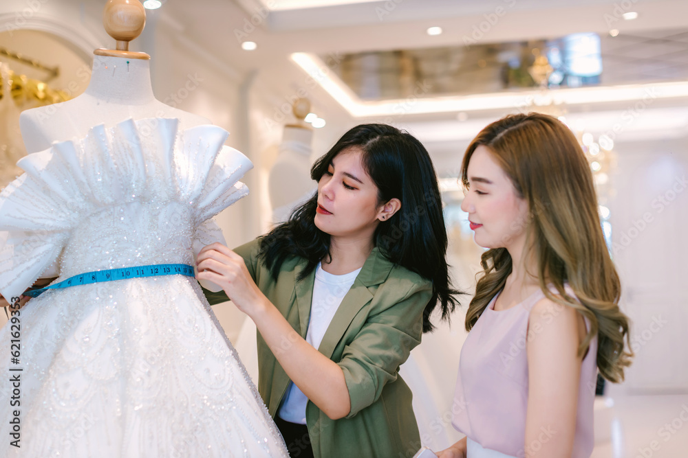 Naklejka premium Female bridal store owner work in wedding studio shop. Owner Of Bridal Wedding Dress Shop Work in shop. Designer woman working wedding dress in store..