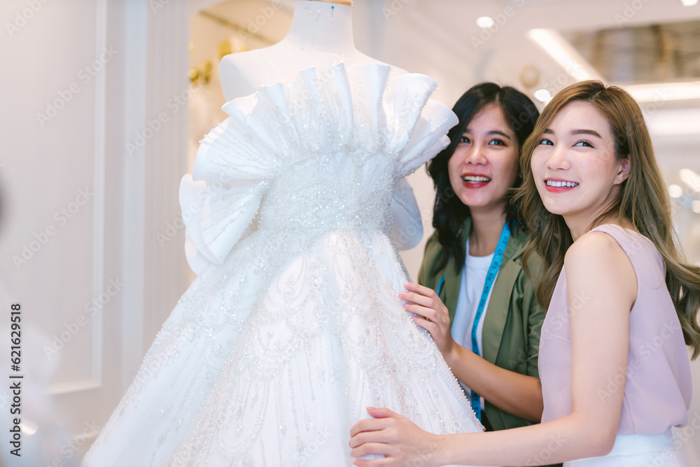 Naklejka premium Female bridal store owner work in wedding studio shop. Owner Of Bridal Wedding Dress Shop Work in shop. Designer woman working wedding dress in store..