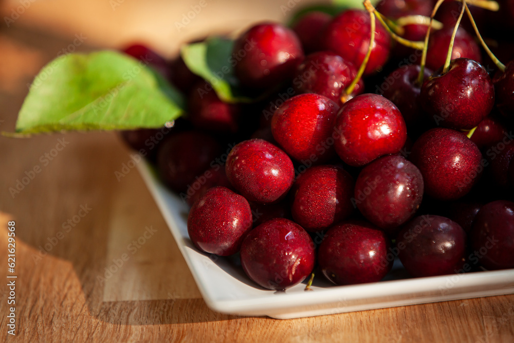 Juicy sweet cherry with water drops on a plate.