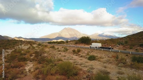 Panning Shot Of Van With Trailer On Road Amidst Plants Near Mountains Against Sky - Baja California, Mexico