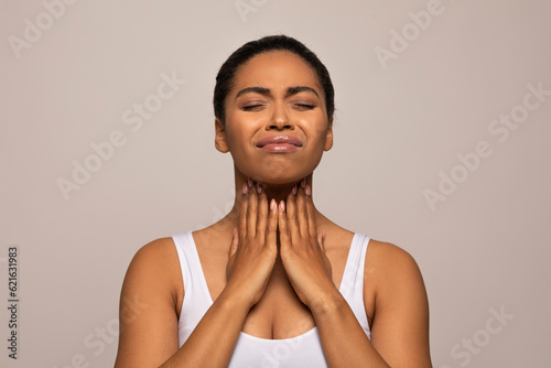 African american woman in pain touching her neck, checking adenoids