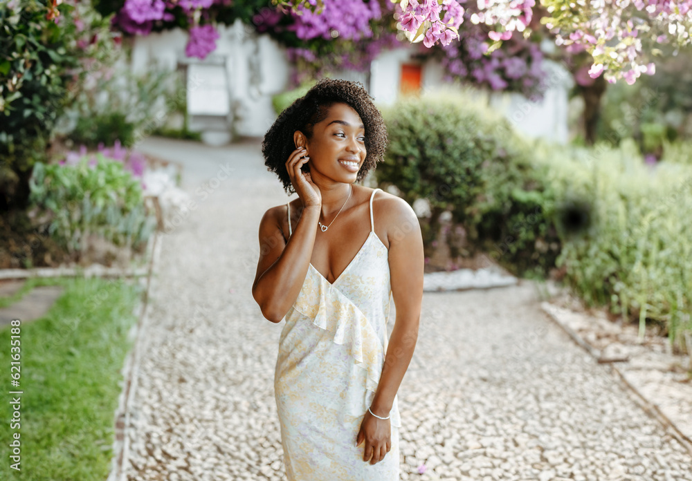 Happy millennial african american woman in dress walks in blooming park, enjoys summer travel Happy millennial african american woman in dress walks in blooming park, enjoys summer travel