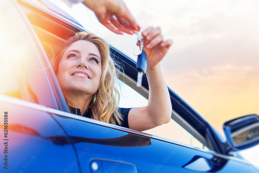A woman's hand passes the key to the car. Buying a car or renting.