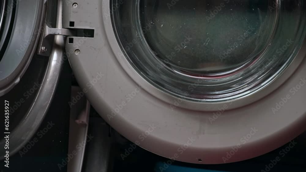 Cleaning of the washing machine. A man wipes the door, the rubber band of the washing machine with a rag. Cleaning of the washing machine. A man wipes the door, the rubber band of the washing machine with a rag.