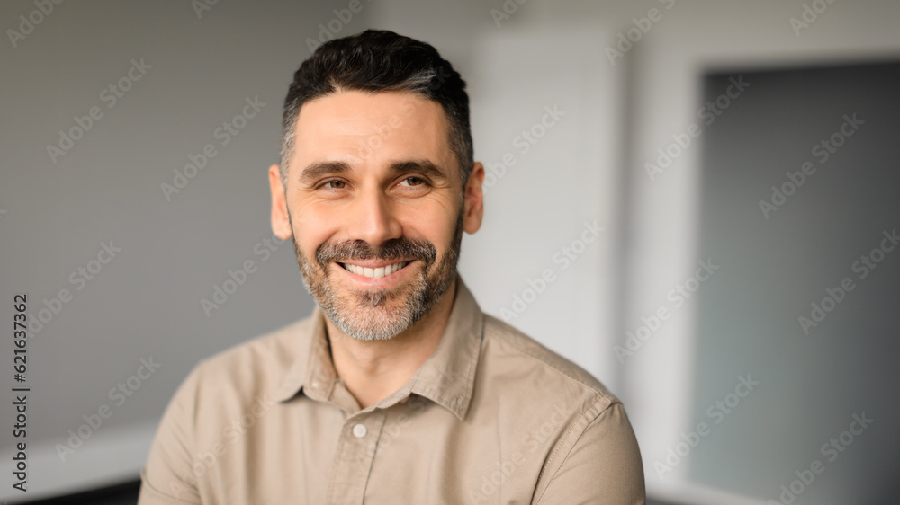 Obraz premium Happy successful european middle aged male entrepreneur looking aside and smiling, office interior, panorama, free space