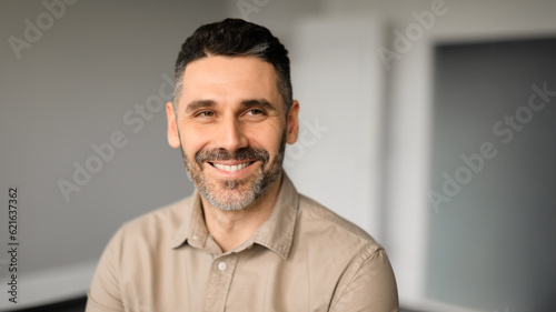 Happy successful european middle aged male entrepreneur looking aside and smiling, office interior, panorama, free space