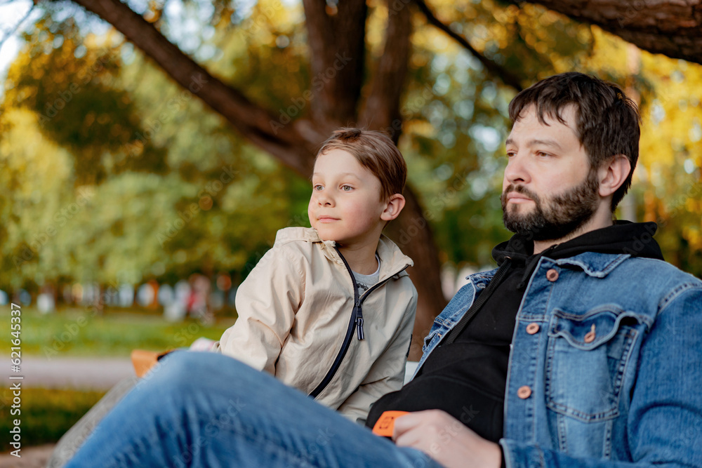 Fototapeta premium Caucasian bearded man with his little son in park on autumn day. Image with selective focus