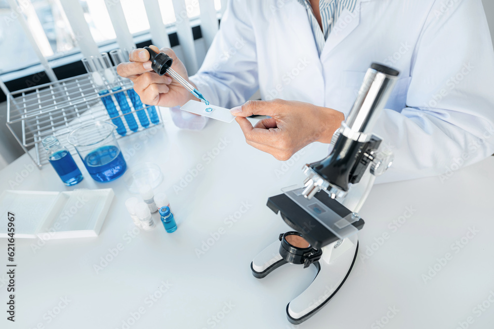 Scientist woman holding dropper to dropping solution sample on t Scientist woman holding dropper to dropping solution sample on t