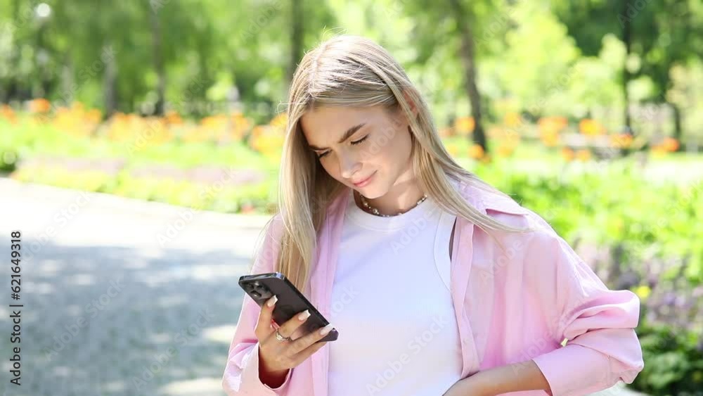 Young beautiful blonde girl with a mobile phone in a summer park Young beautiful blonde girl with a mobile phone in a summer park