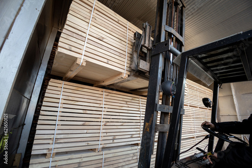 Φωτογραφία A diesel forklift loads freshly sawn pine logs, girders, bars, beams, bars, boards into a drying chamber
