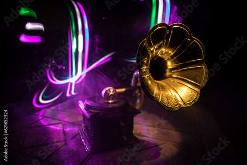 Music concept. Old gramophone on a dark background. Retro gramophone with disc on wooden table with toned backlight.