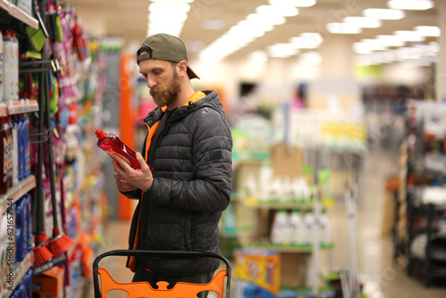 A bearded Caucasian man customer is interested in cleaning products at the supermarket. Copy space for text, advertising, message, logo