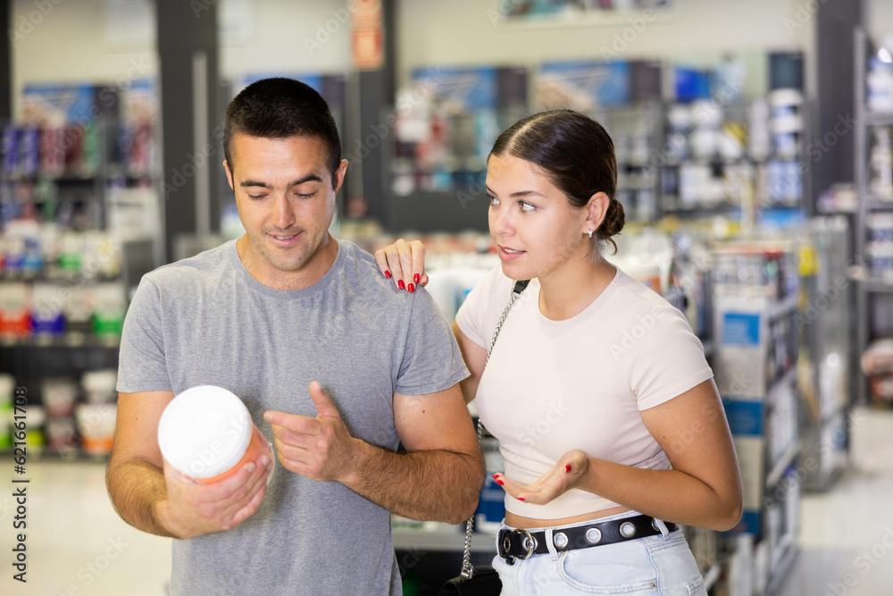 Married couple choosing a can of paint together in a hardware store