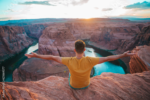 Happy man on the edge of the cliff. Horseshoe Bend Canyon in Page, Arizona. Adventure and tourism concept