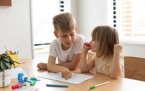 The older brother teaches the younger sister to read letters. Brother and sister, home schooling.
