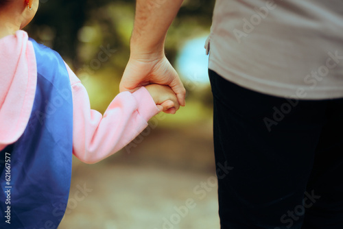 Father and Daughter Wearing Superhero Cape Holding Hands. Happy family talking a walk outside together 
