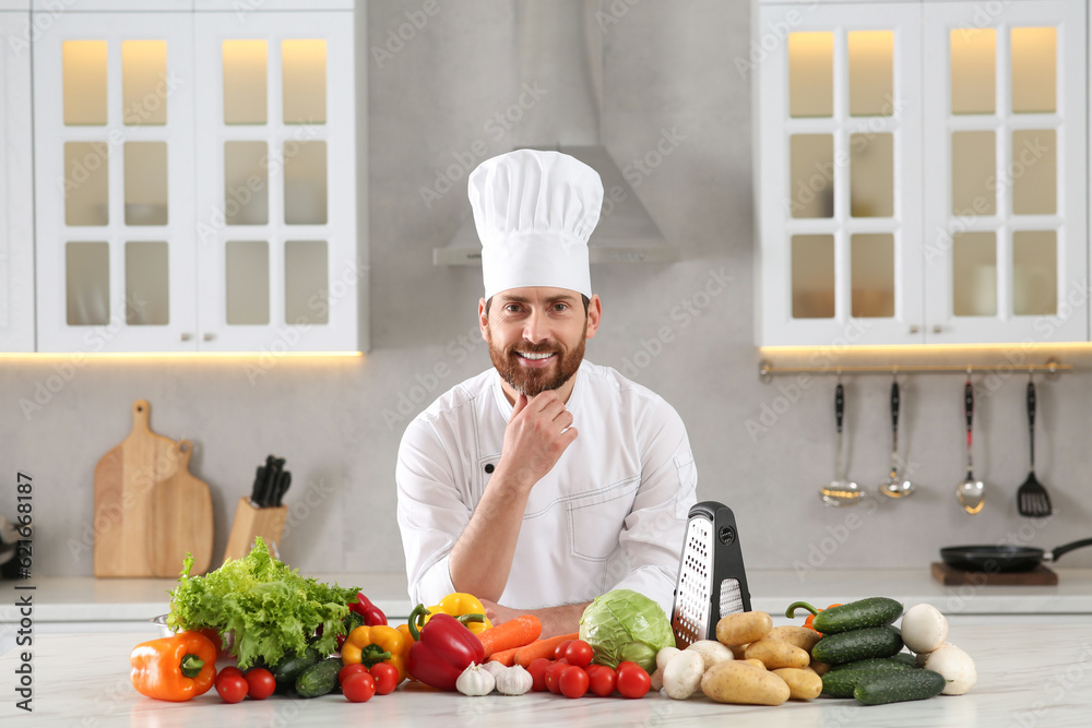 Portrait of happy professional chef near vegetables at marble table in kitchen Portrait of happy professional chef near vegetables at marble table in kitchen