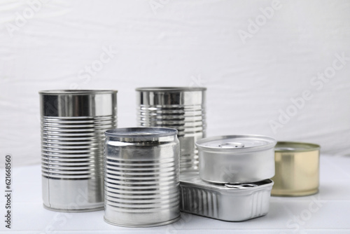 Many closed tin cans on white tiled table